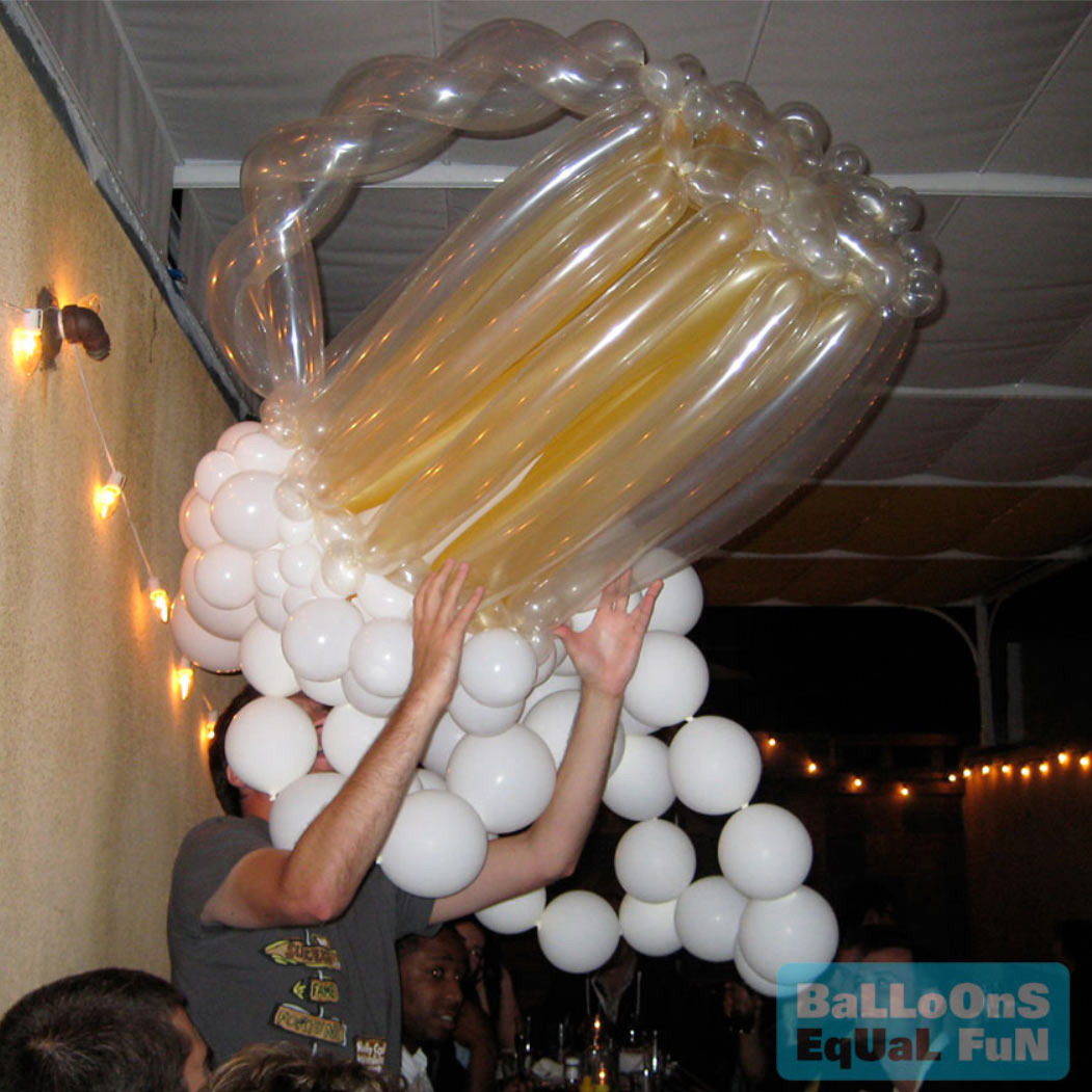 Giant balloon beer which is being held up by a guest as if drinking it. The balloon beer suds drape and hang, obscuring the face.