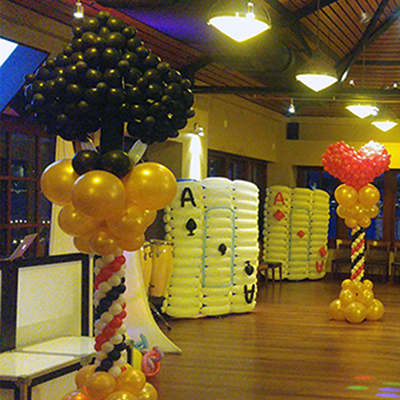 Giant ballon playing cards, and 2 columns. The columns have toppers. One is a black spade and the other a red heart.